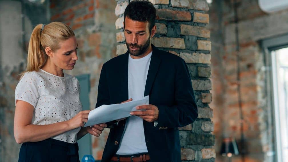 Man and woman looking at paper in brick building