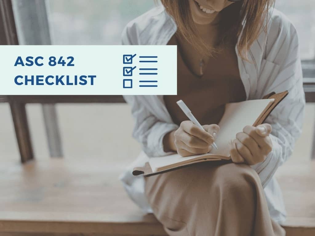 Woman writing ASC 842 checklist in notebook