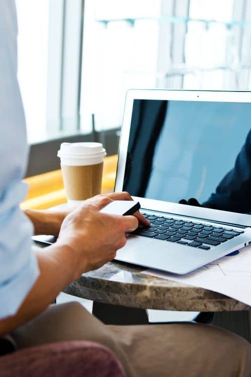 Person sitting while using laptop and phone